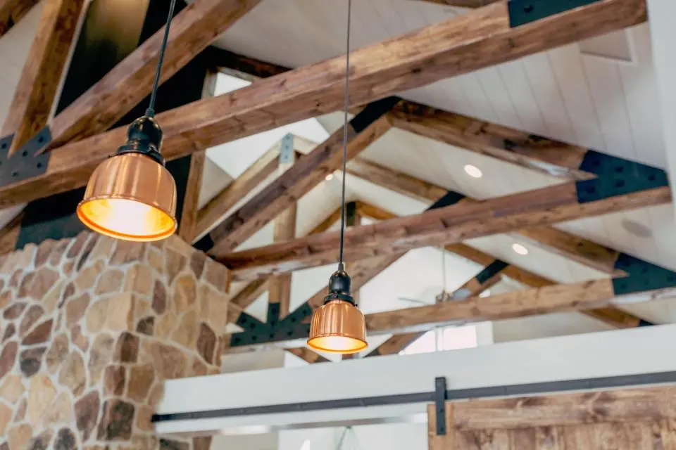 A vaulted ceiling with exposed timber beams and copper pendant lights