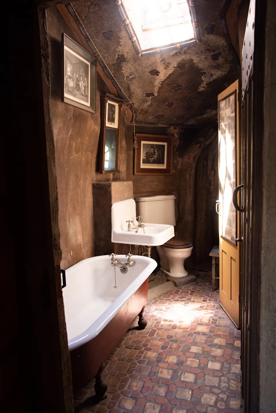 A small bathroom with a roll-top bath and dark panelled walls