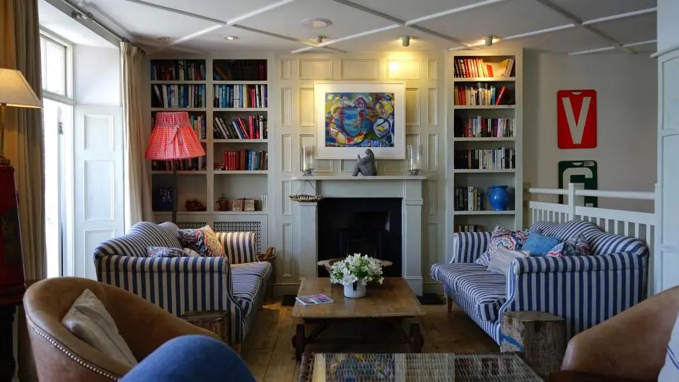 A sitting room with striped sofas, a fireplace and built-in bookshelves