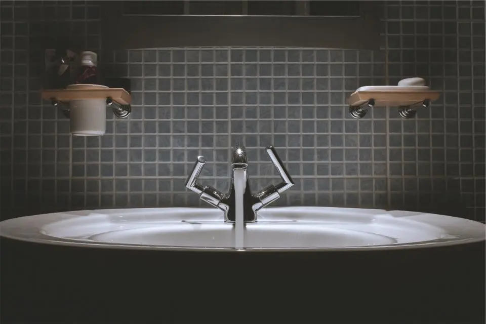 A grey tiled bathroom wall above a white basin