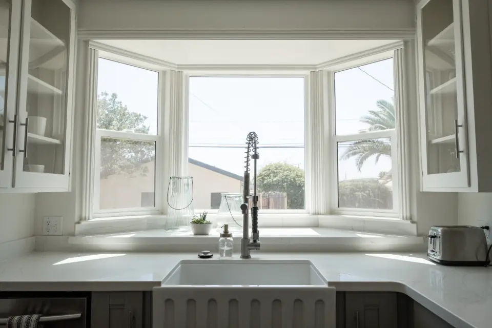 A farmhouse kitchen sink beneath a bay window