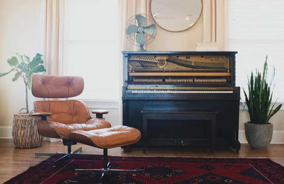A living room with an upright piano, a leather lounge chair and a Persian rug