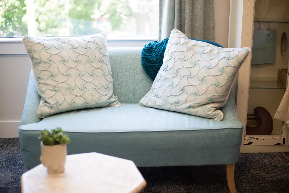 A pale blue loveseat with patterned cushions