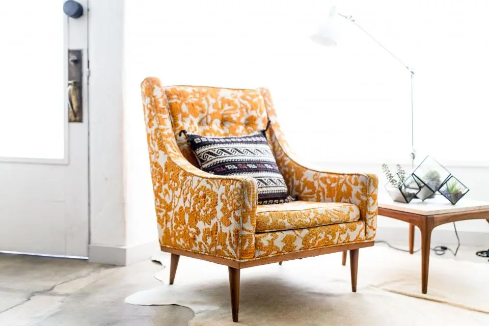 A mustard patterned armchair in a white room